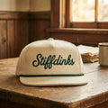 Beige cap with 'Stiffdinks' logo on a wooden surface